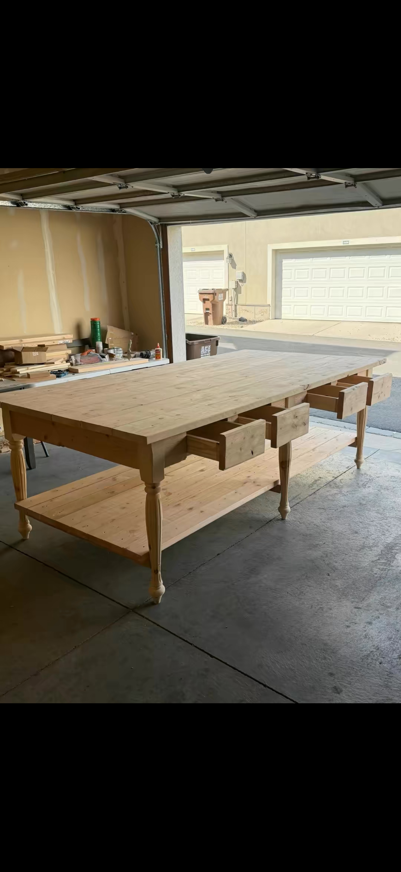 The drawer island. A light wood island with turned legs, multiple drawers and a full lower shelf, shown in the workshop.