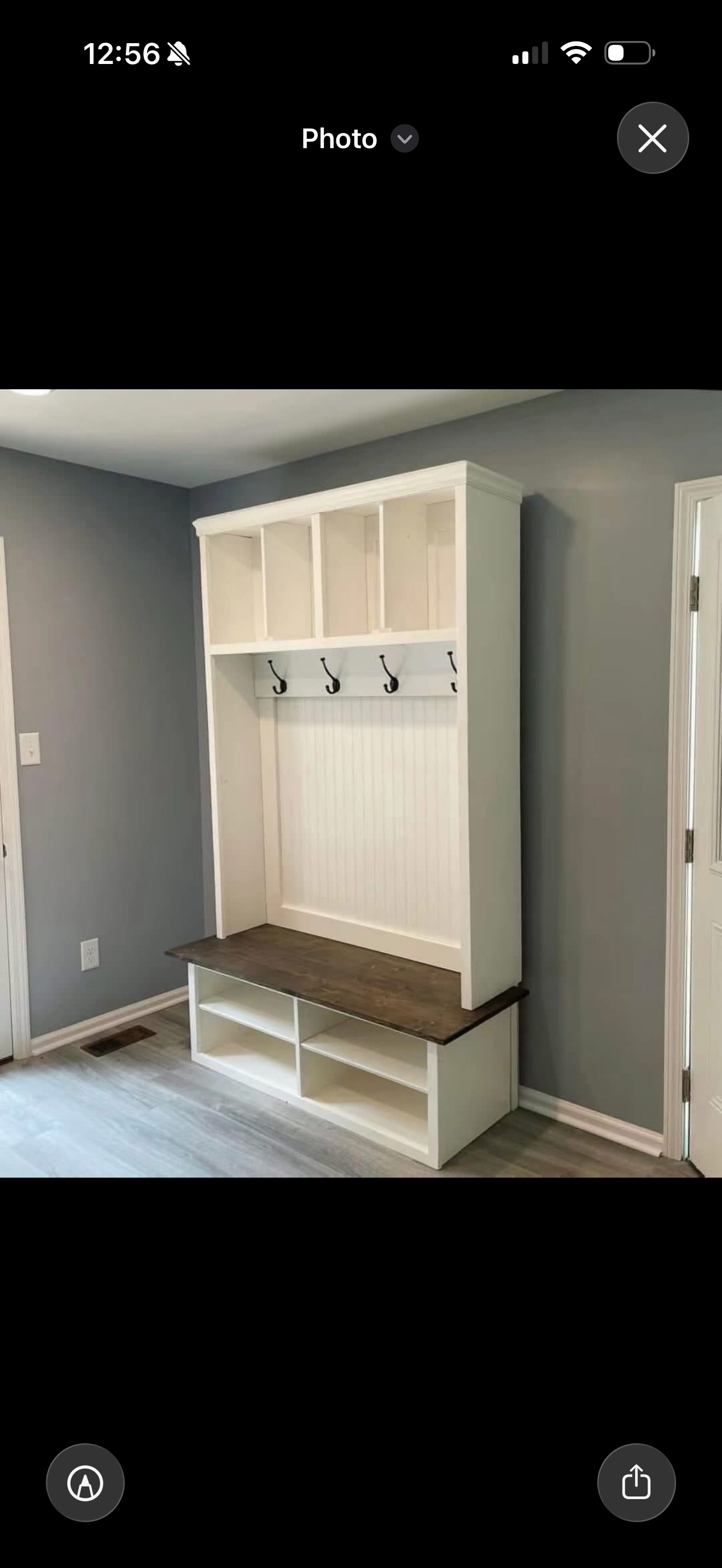 The cubby hall tree. White storage cubbies, black hooks and a wood bench seat with shoe shelves.