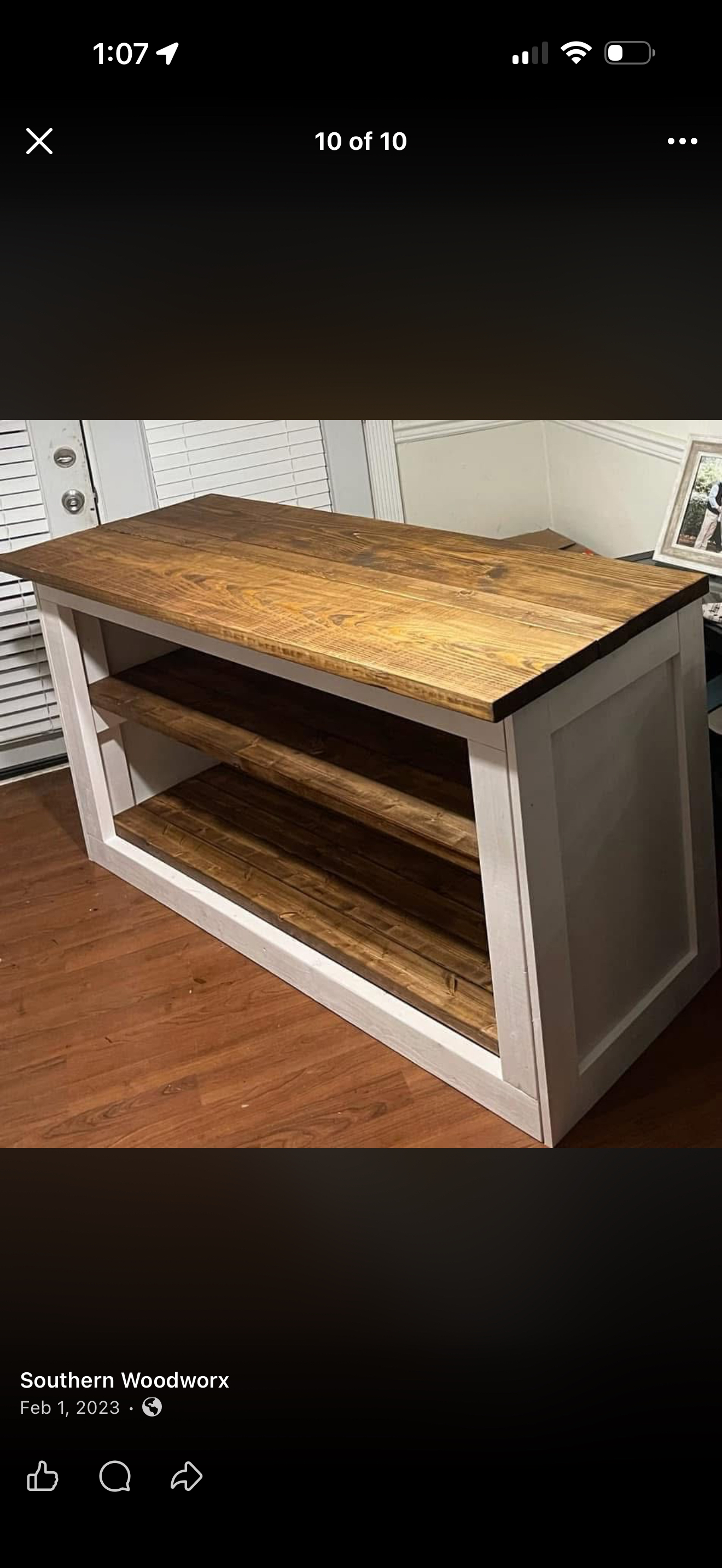 The white kitchen island. A warm wood top with a white base and two open shelves.