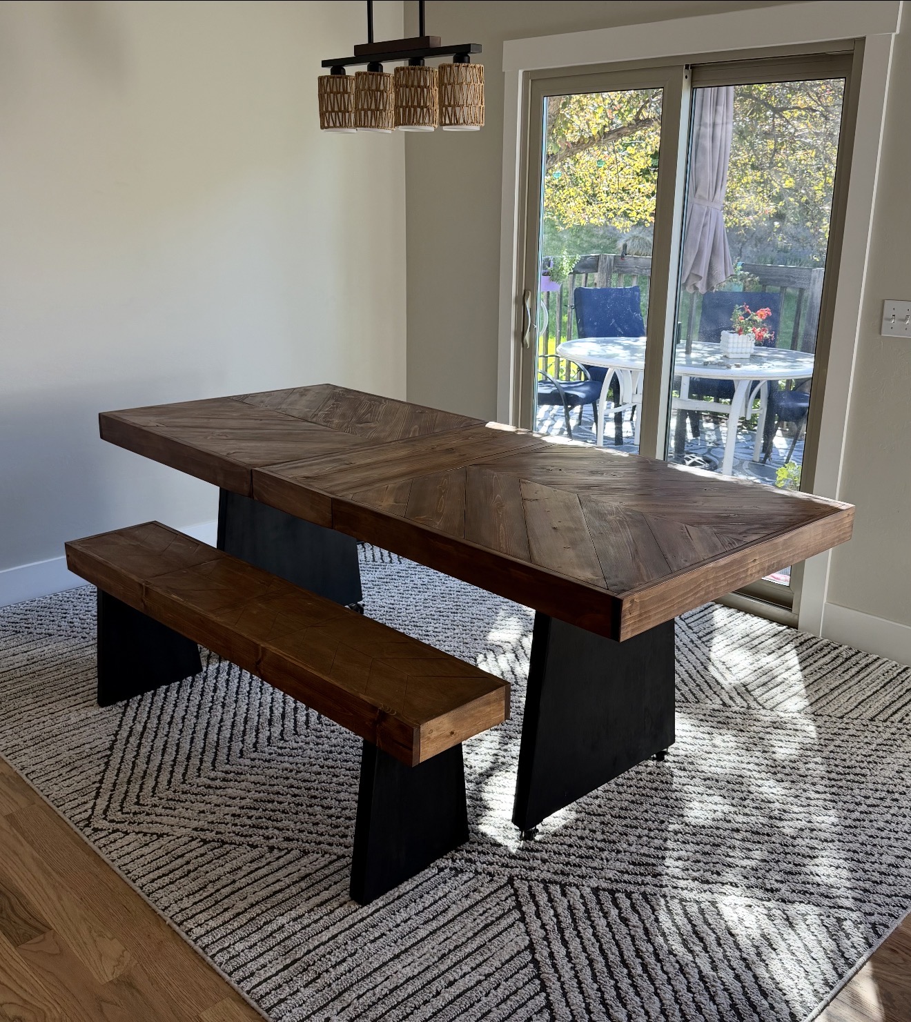 Geometric dining table and bench. Patterned wood tops paired with bold black bases.