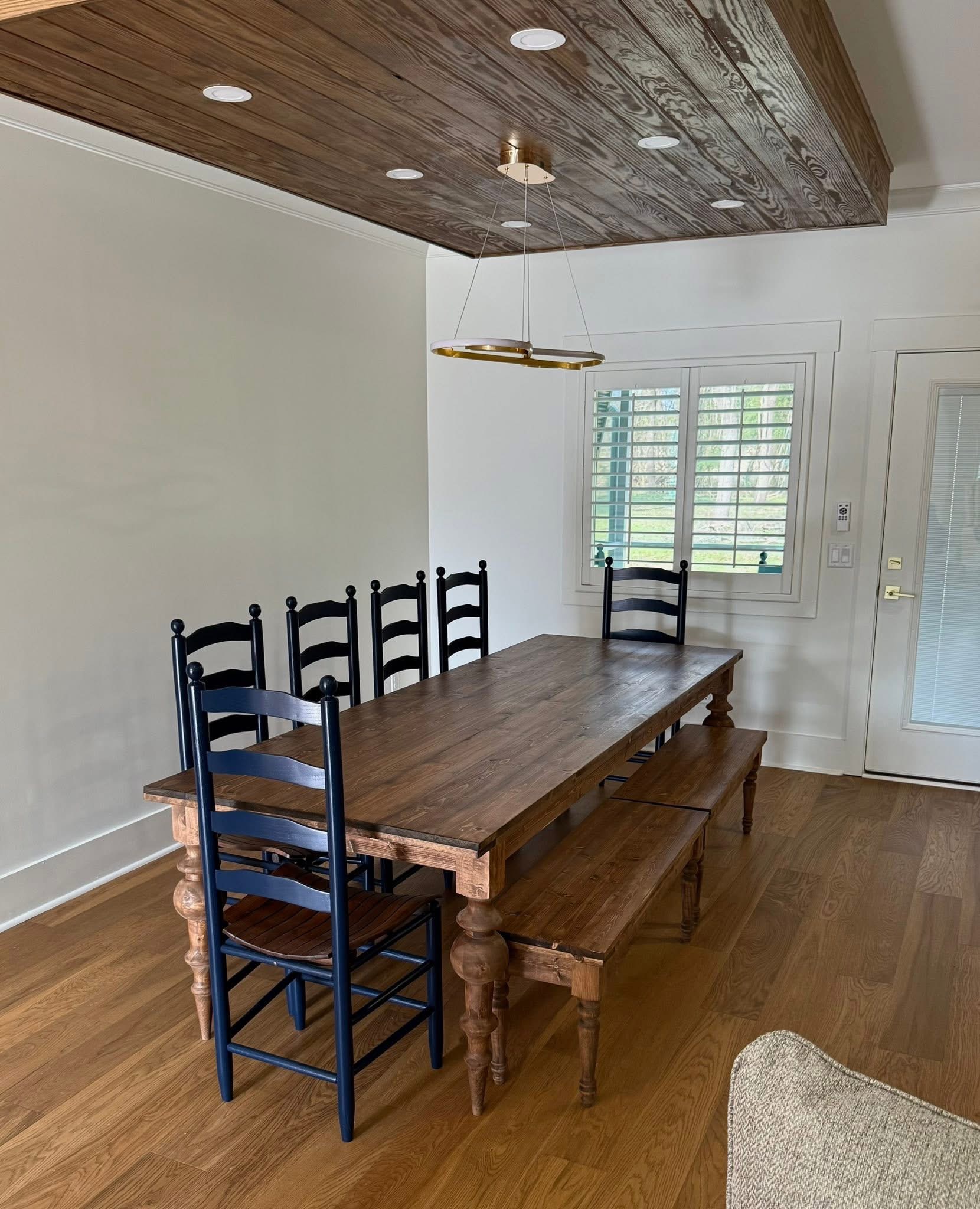 Long dining table with bench. A warm wood table and matching bench, shown with dark ladder-back chairs.